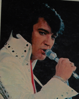 Photo d'Elvis Presley en costume de scène blanc, micro à la main